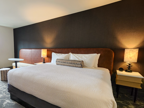 A modern bedroom with a large bed, two bedside tables with lamps, and a dark accent wall, creating a cozy ambiance.