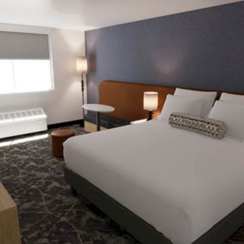 A hotel room with two twin beds, a desk, a chair, a wall-mounted lamp, and soft lighting in a modern, cozy setting.